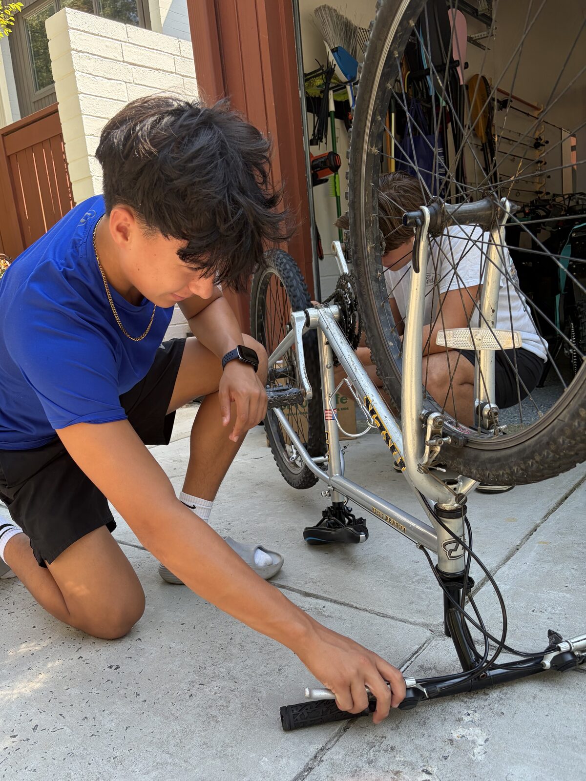A Success Cycles student refurbishing a donated bike in the driveway